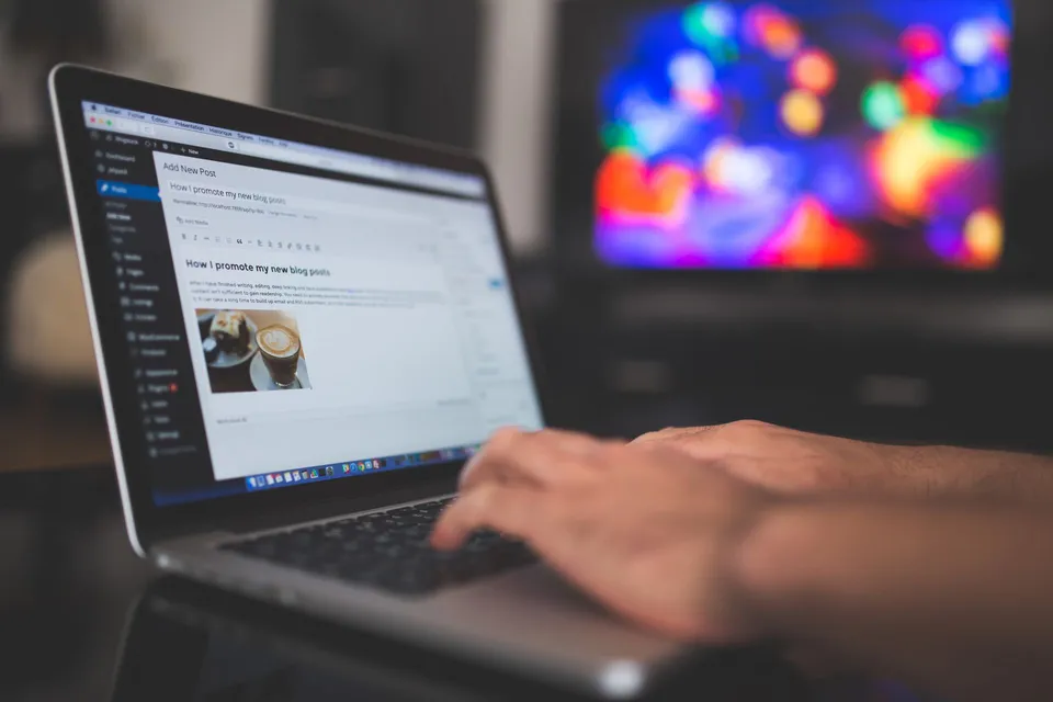 Hands typing on a laptop while editing a website post.